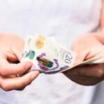 Close-up as a woman counts out modern British banknotes.